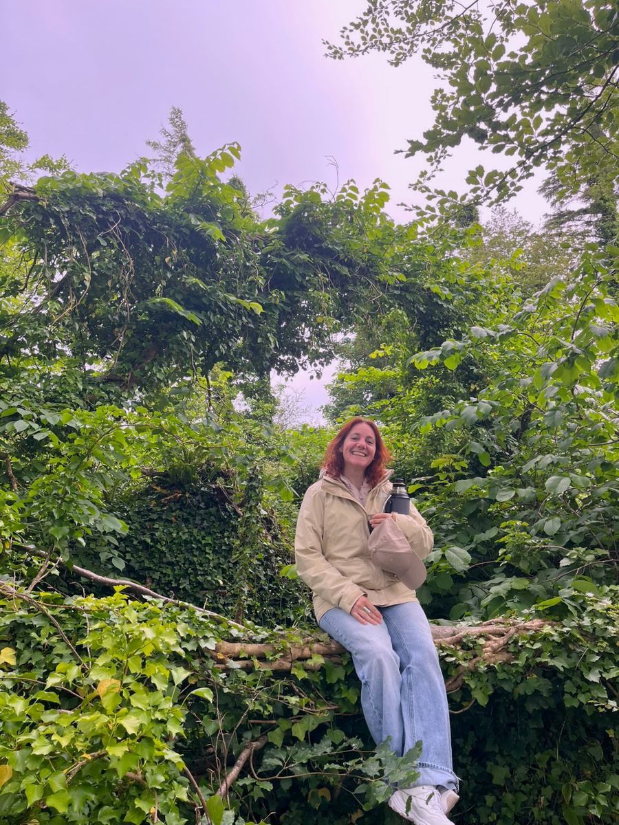 Nela sentada en un puente cubierto de vegetación